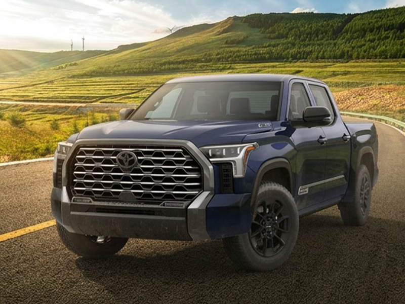 A blue Toyota truck parked on a scenic road surrounded by green hills and a clear sky, showcasing its rugged design and features.