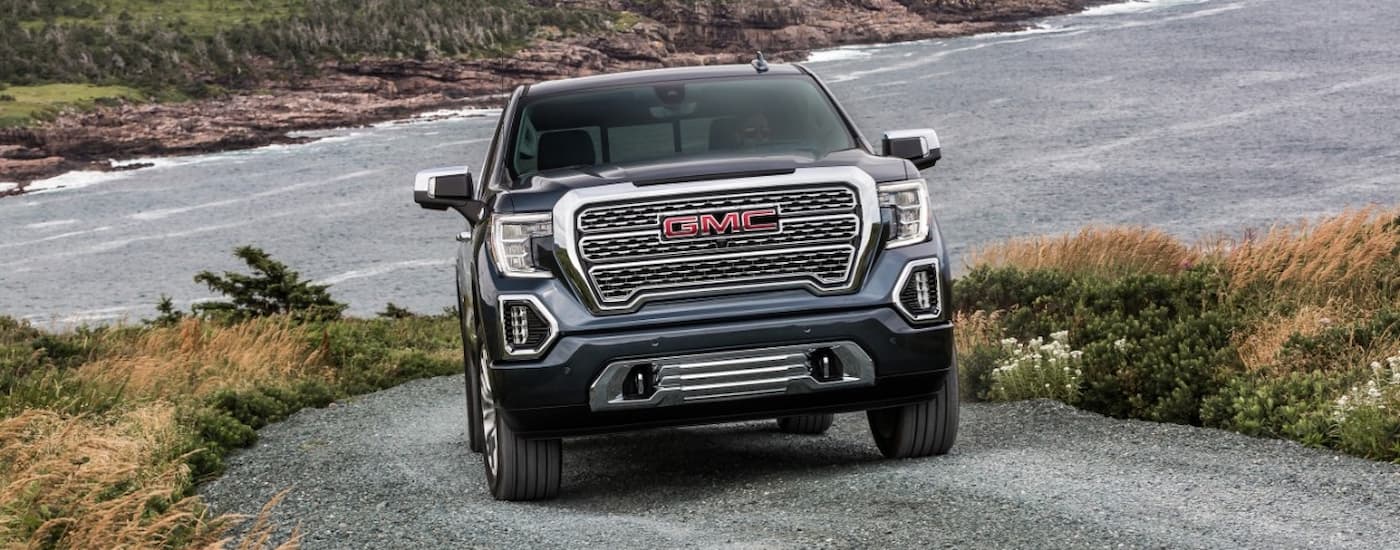 A grey 2020 GMC Sierra 1500 is shown from the front driving on a gravel road.