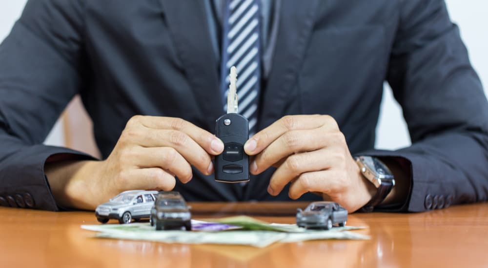 A car salesman is shown holding a car key after speaking with a customer about bad credit car financing.