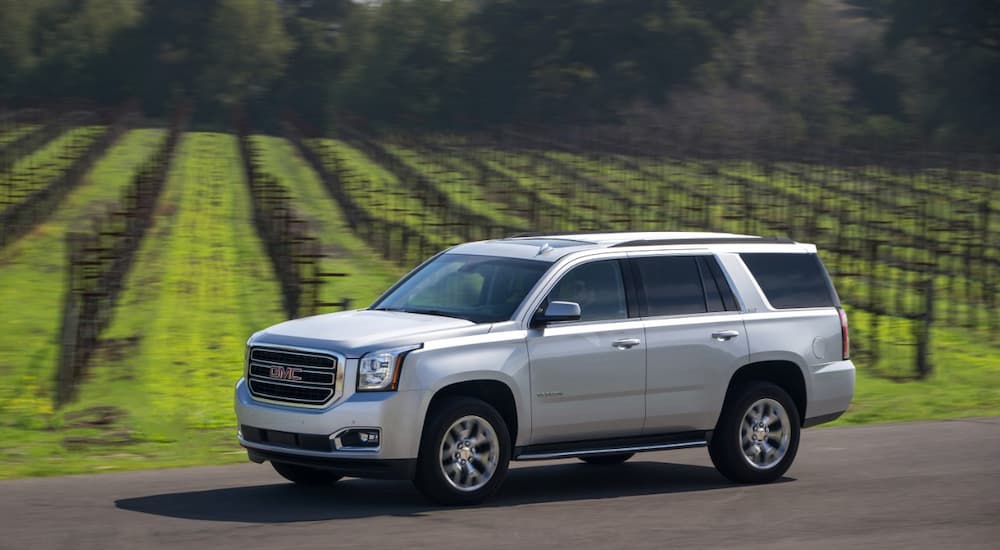 A silver 2017 GMC Yukon SLT is shown driving next to a farm after researching bad credit financing near Meridian Township, MI.