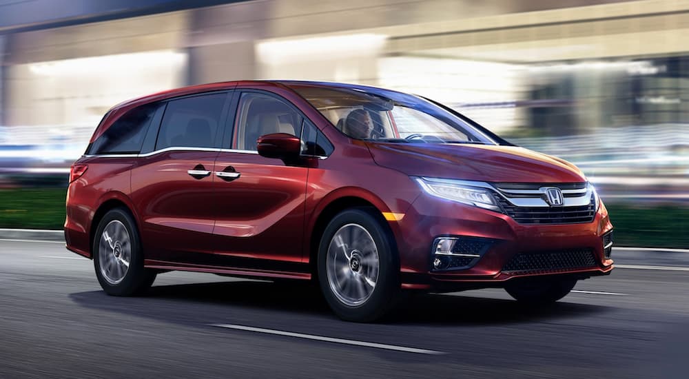 A red 2020 Honda Odyssey is shown driving on a city street at night.