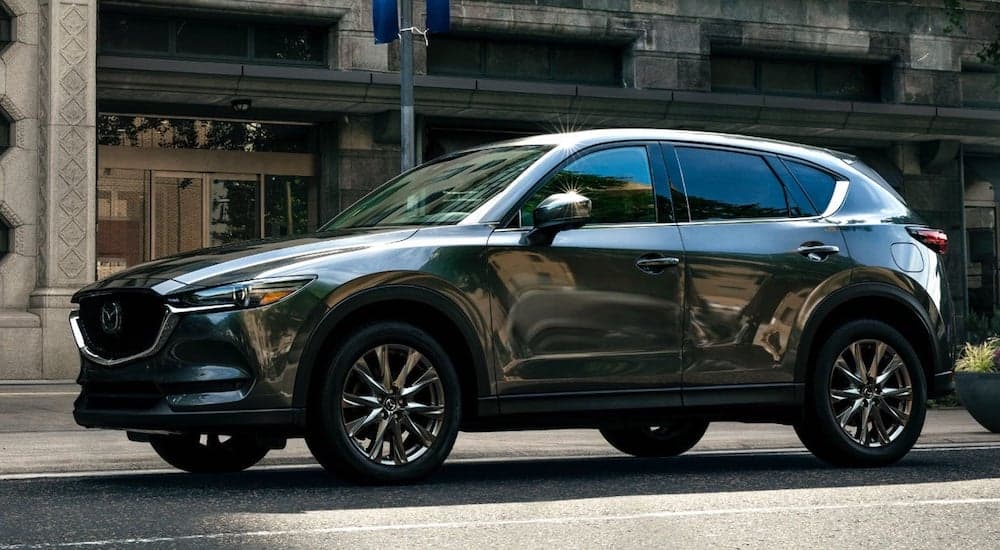 A dark grey 2021 Mazda CX-5 is shown on a city street after visiting a dealership that does buy here pay here near you.