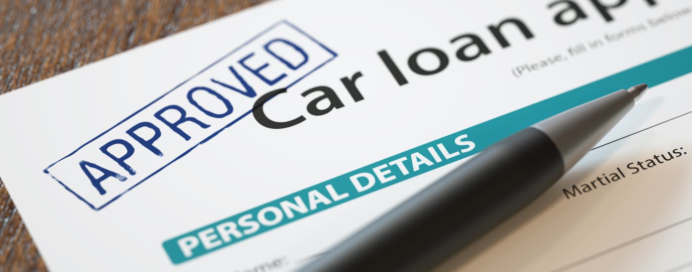 A close up shows 'approved' stamped on car loan paperwork.