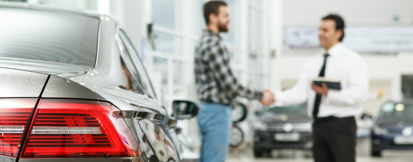 A customer is shown shaking a salespersons hand at a dealership that does buy here pay here near you. 