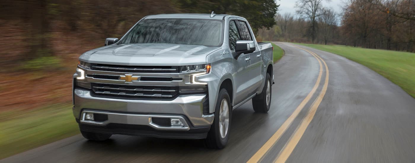 A silver 2019 Chevy Silverado 1500 LTZ is shown driving on a wet road.