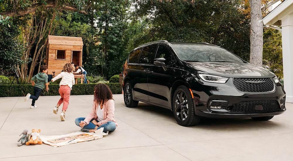 Children are shown playing in a driveway next to a black 2021 Chrysler Pacifica.