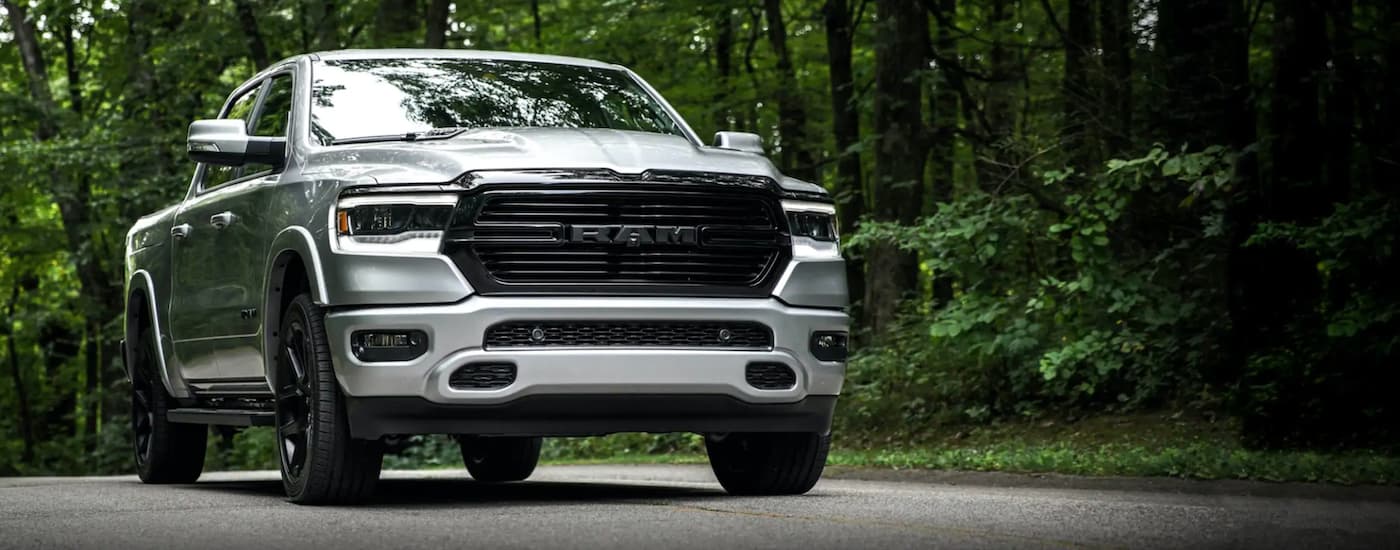 A silver 2020 Ram 1500 is shown on a tree-lined road.