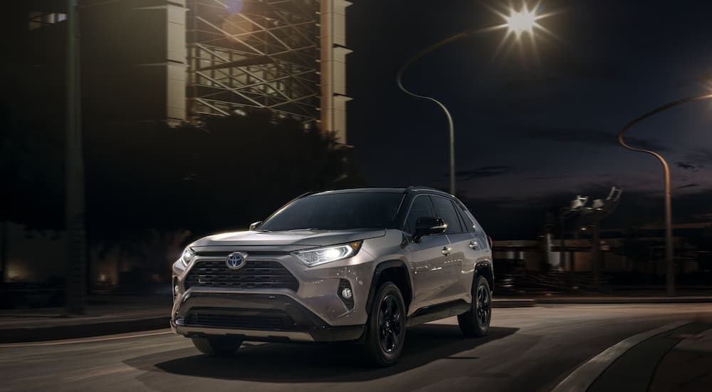A silver 2020 Toyota RAV4 is shown driving on a city street at night.