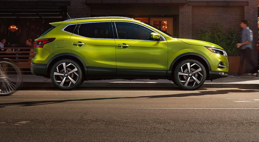 A green 2021 Nissan Rogue Sport is shown from the side on a city street.