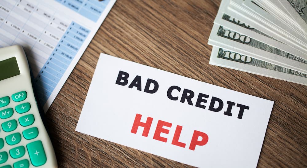 A piece of paper that says 'bad credit help' is shown on a table.
