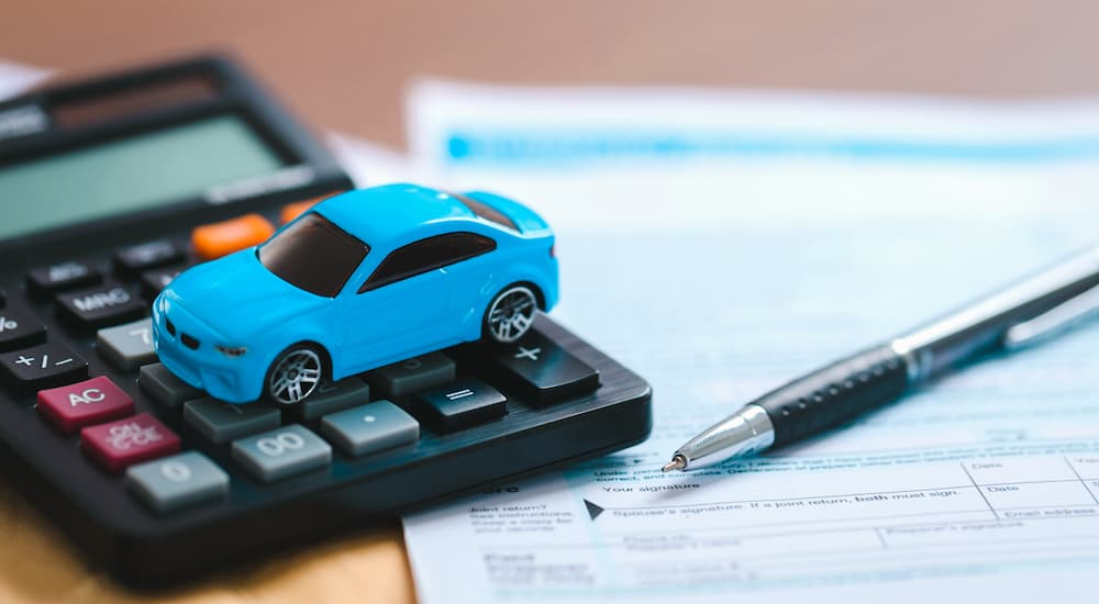 A blue toy car is shown next to auto loan paperwork.