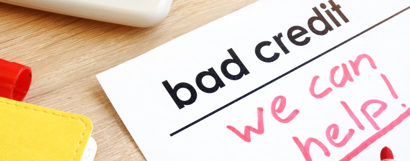 A piece of paper that says 'bad credit we can help' is shown on a table.