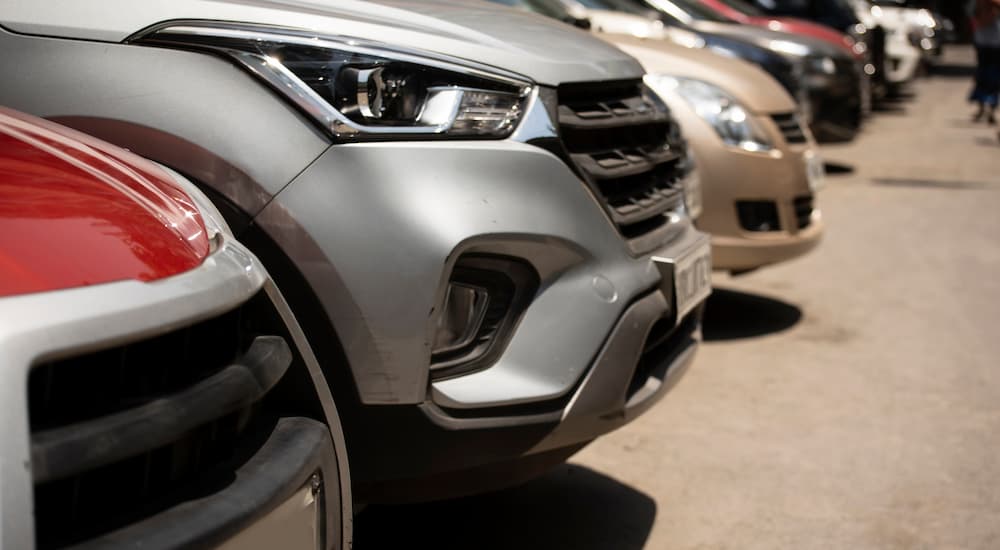 A close up of the front of vehicles shown in a row at a used car lot is shown.