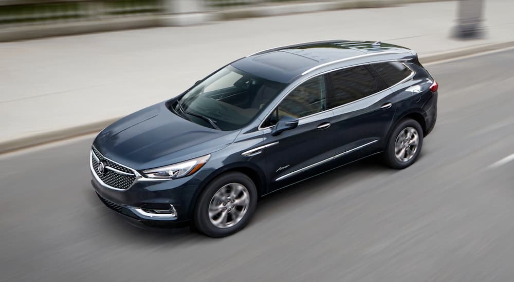 A blue 2018 Buick Enclave Avenir is shown driving on an open highway.